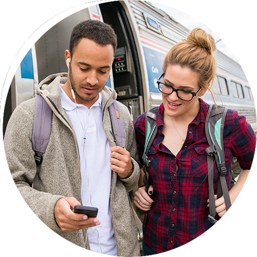 Young people look at mobile phone on a train platform