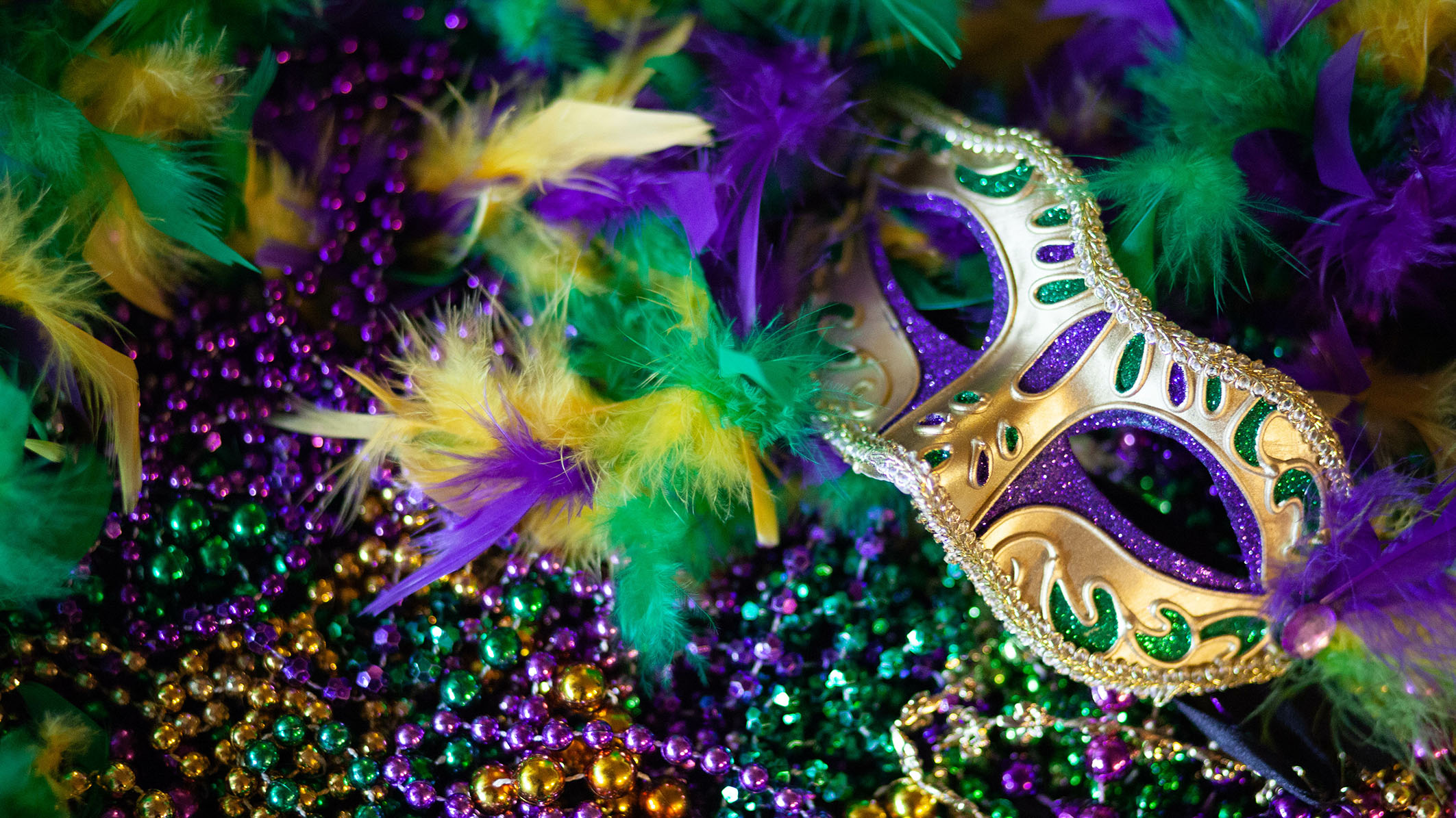 Purple, gold and green mardi gras mask, beads and feathers decor background